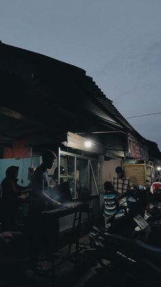 some people sitting at a table in front of a building with a light on it