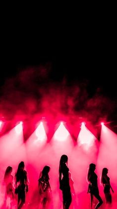 a group of women standing on top of a stage under spotlights in front of red and white lights