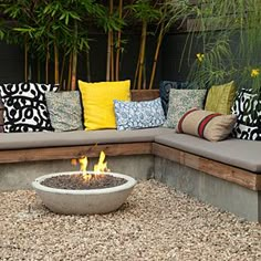 an outdoor fire pit surrounded by gravel and pillows