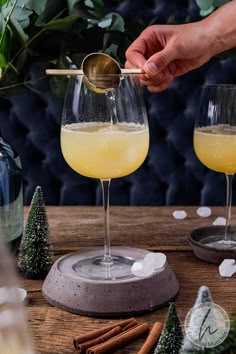 two glasses filled with yellow liquid sitting on top of a wooden table