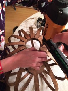 a person using a drill to cut out wood circles