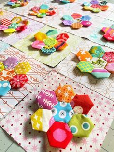 several colorful pieces of fabric are laid out on the table top, and one is folded in half to make an origami flower