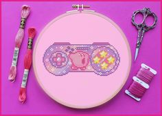 a cross stitch pattern with scissors and thread on a pink background next to some yarn