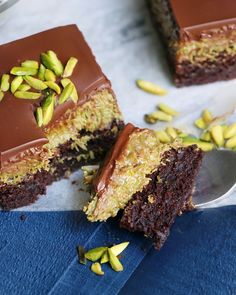 there is a piece of cake with chocolate frosting and pistachios on it