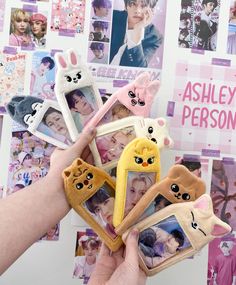 a person holding up several small stuffed animals in front of a wall with pictures on it