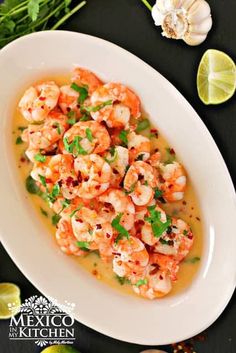 a white plate topped with cooked shrimp and garnished with cilantro sauce