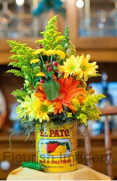 an arrangement of flowers in a can on a table