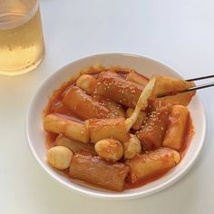 a white bowl filled with food next to a glass of beer on top of a table