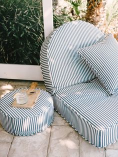 two blue and white striped chairs sitting next to each other on a tile floor with plants in the background