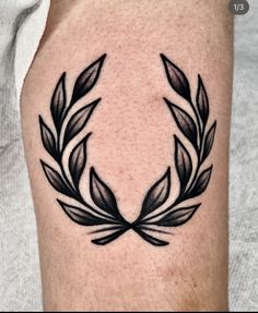 a black and white photo of a man's arm with a wreath tattoo on it