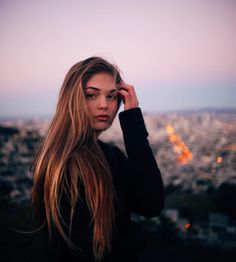 a woman with long hair standing in front of a cityscape