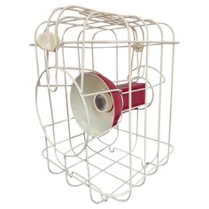 a white bird cage with a roll of red tape in the center and two rolls of toilet paper on each side