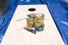 two cans of paint sitting on top of a wooden board