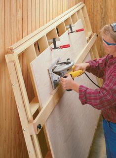 a man using a power drill to attach wood pieces on the wall in his workshop