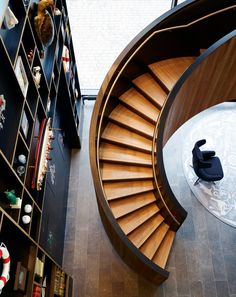 a spiral staircase in the middle of a living room with bookshelves and shelves