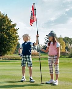 two young children holding up a flag on a golf course