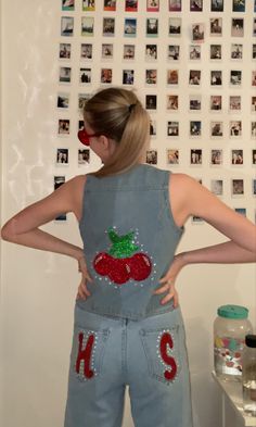 a woman with her back to the camera wearing denim overalls that have cherries on them