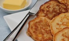 some pancakes and butter on a plate with a fork next to it, ready to be eaten