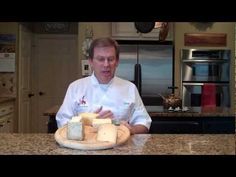 a man in a chef's uniform sitting at a counter with cheese on it