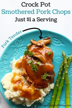 a blue plate topped with mashed potatoes covered in gravy and asparagus