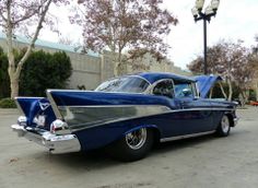 an old blue car parked in a parking lot next to a street light and lamp post