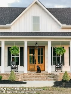 a dog sitting on the front steps of a white house with black shutters and potted plants