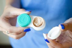 a woman is holding two containers with creams in them and one container has an open lid