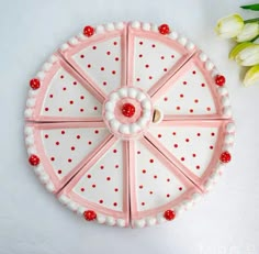 a pink and white decorative tray with red dots on the rim next to tulips