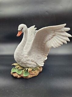 a white swan figurine sitting on top of a rock