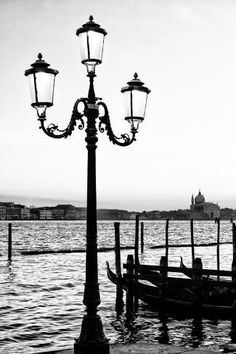 a black and white photo of a lamp post with gondolas in the background