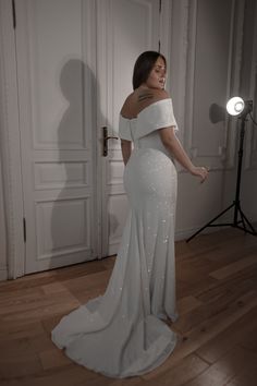 a woman standing in front of a door wearing a white dress with sequins on it