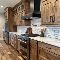 a kitchen with wooden cabinets and stainless steel stove top oven in the center, surrounded by hardwood flooring