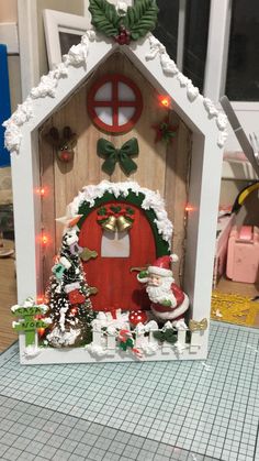 a small christmas house with lights and decorations on the front, sitting on a table