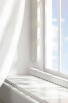 an empty window sill in front of a white curtain with the sun shining through