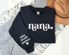 two sweatshirts with the word nana on them next to a hat and scarf