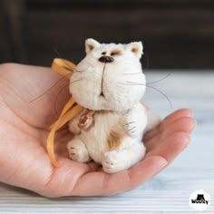 a hand holding a small stuffed animal in it's palm