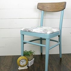 a blue chair sitting on top of a wooden floor next to a potted plant