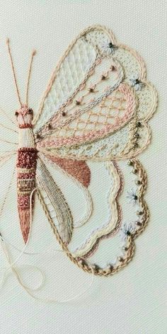 a close up of a butterfly on a piece of white fabric with pink and red thread