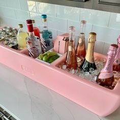 a pink tray filled with bottles and glasses on top of a counter next to a stove