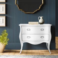 a white dresser sitting next to a blue wall with a mirror on top of it