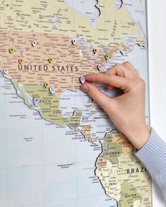 a person pointing to the united states on a world map with pins in each country