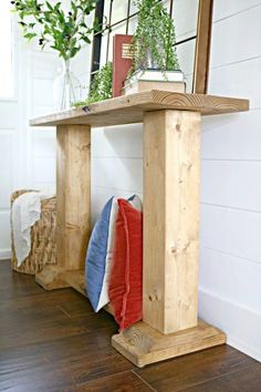 a wooden table sitting on top of a hard wood floor next to a mirror and potted plant