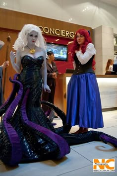 two women dressed in costume standing next to each other on the floor at a convention