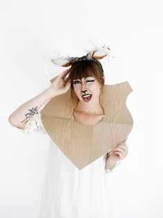 a woman with fake antlers on her head is holding a cardboard bag over her face