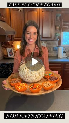 a woman holding a platter full of food with the words fall popcorn board for entertaining