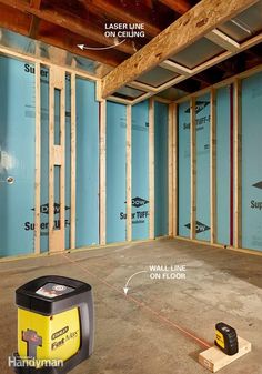 an unfinished room with blue walls and wood framing around the wall, including a yellow machine