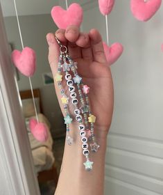 someone is holding up some pink heart shaped beads with the words love on them and stars hanging from strings