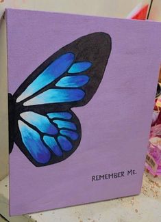 a painting of a blue butterfly on a purple background with the words, remember me