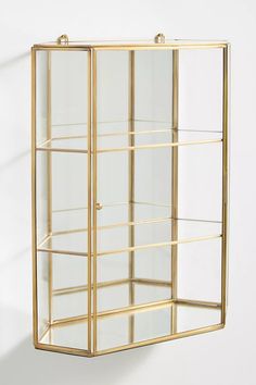 a gold metal and glass display case against a white wall