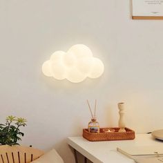 a white table topped with a basket filled with candles next to a wall mounted cloud